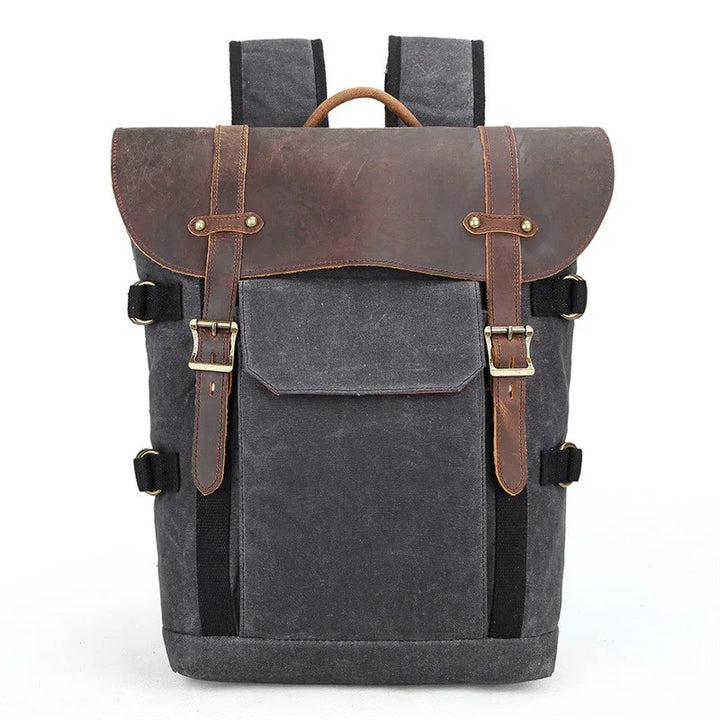 Stylish black canvas backpack with brown leather flap, adjustable straps, and front pocket on white background