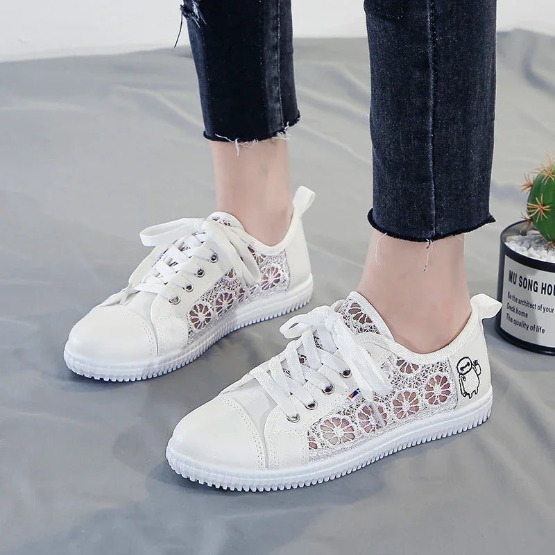 White lace floral sneakers with cartoon ghost detail worn with black cropped jeans on gray floor