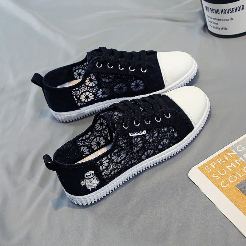 Black and white lace sneakers with floral patterns and white toe caps on gray surface