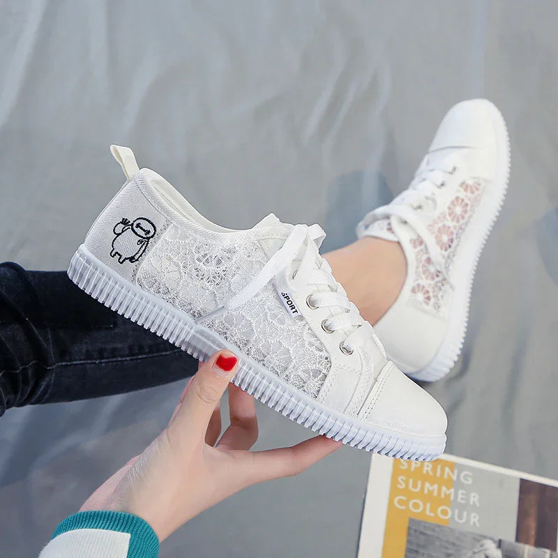 White lace sneakers with cartoon patch and lace-up detail, held above grey surface and magazine