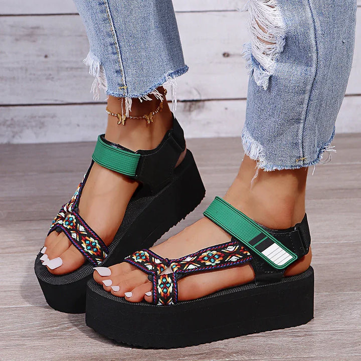 Women wearing black platform sandals with colorful straps and green ankle straps, paired with ripped light blue jeans