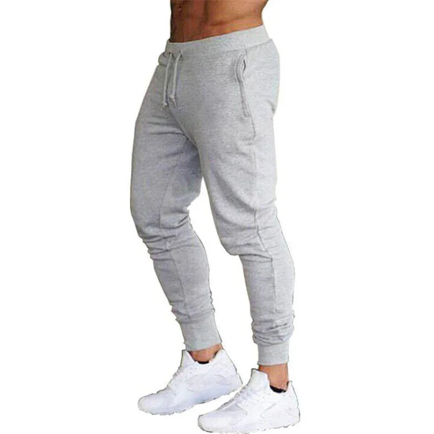 Man wearing heather gray slim fit joggers with drawstring waist and white sneakers on white background