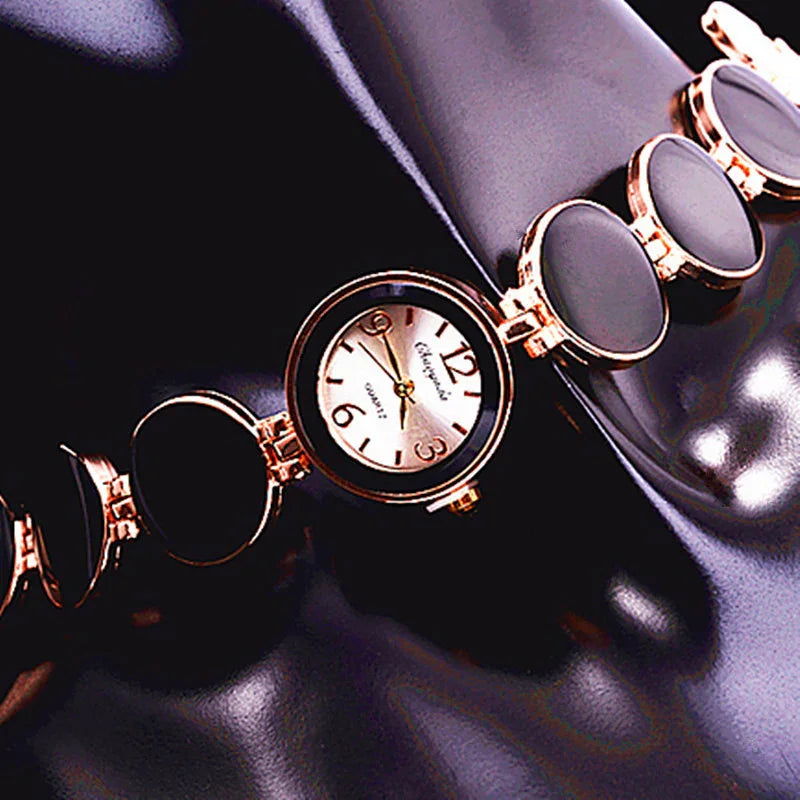 Elegant quartz wristwatch with rose gold circular links and black insets on glossy black surface