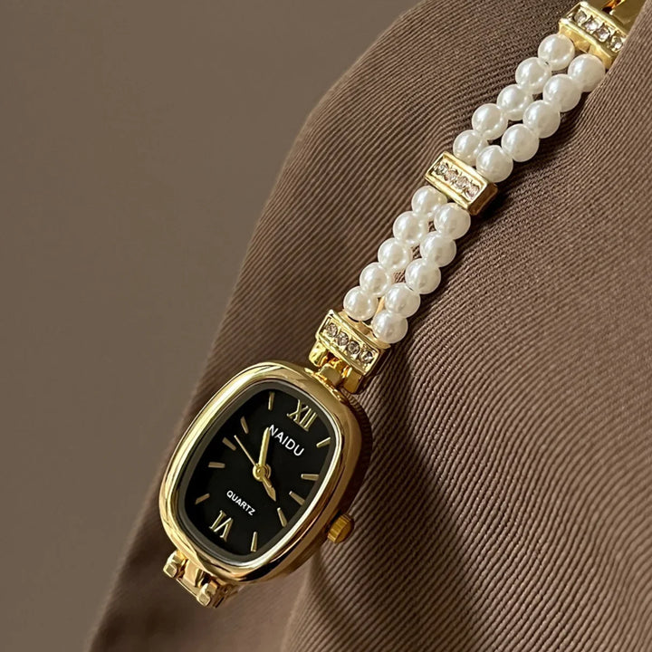 Elegant gold NAIDU quartz wristwatch with black dial and pearl bracelet detail