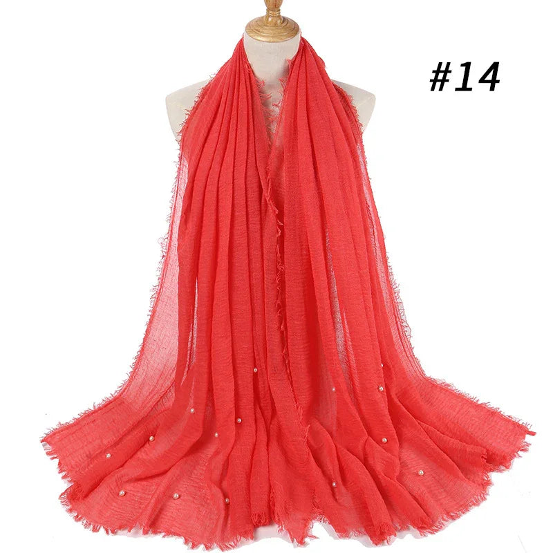 Red lightweight scarf with frayed edges and small pearl embellishments draped on mannequin