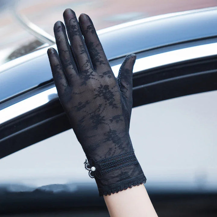 Hand wearing elegant black lace glove with floral pattern and decorative pearl detail