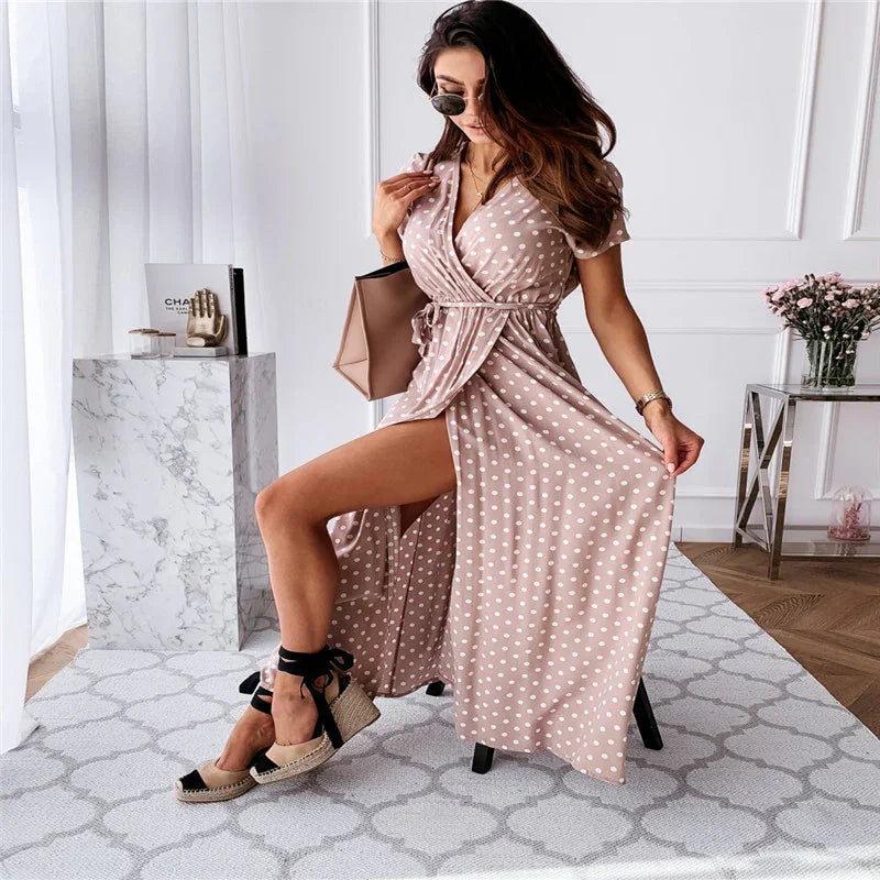 Woman in pink polka dot wrap dress with black espadrille wedges posing in chic white room