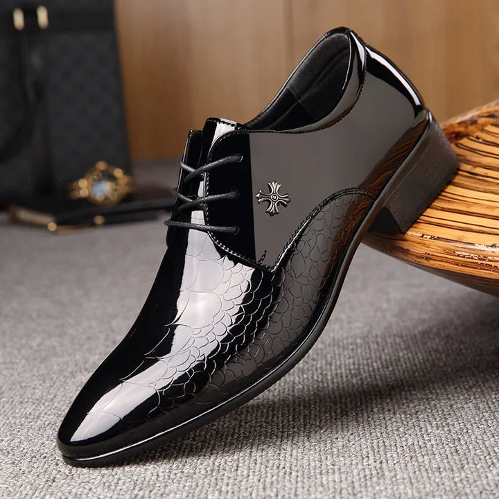 Black glossy men's dress shoe with textured pattern and decorative emblem on side