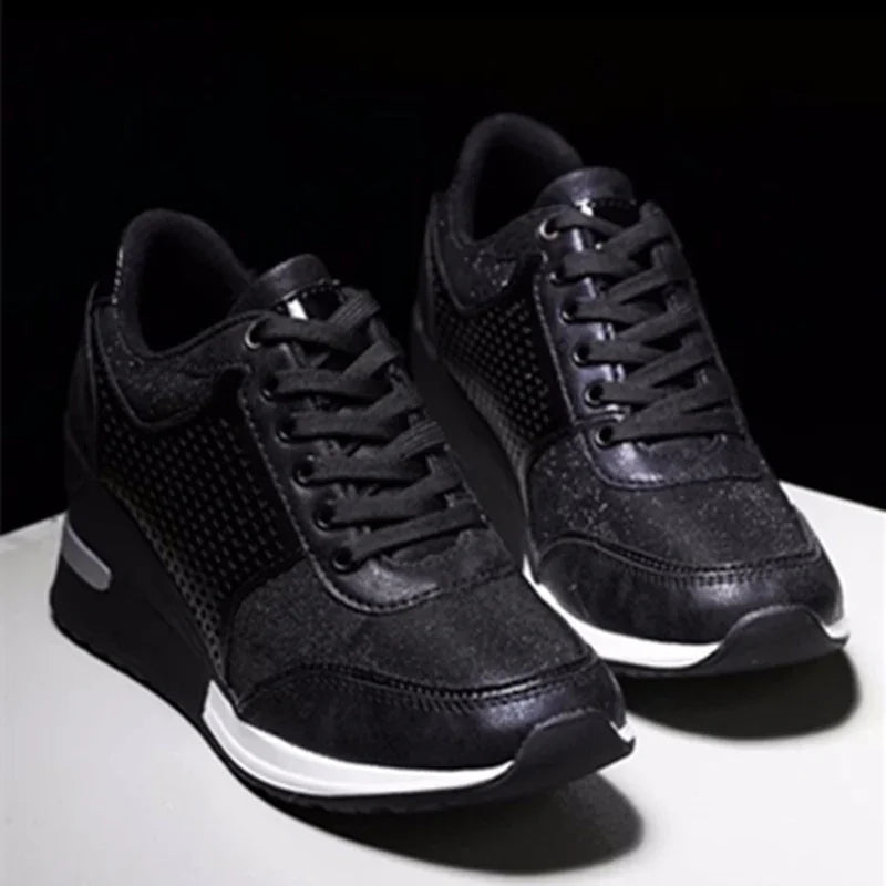 Pair of black athletic sneakers with mesh and leather details on white surface