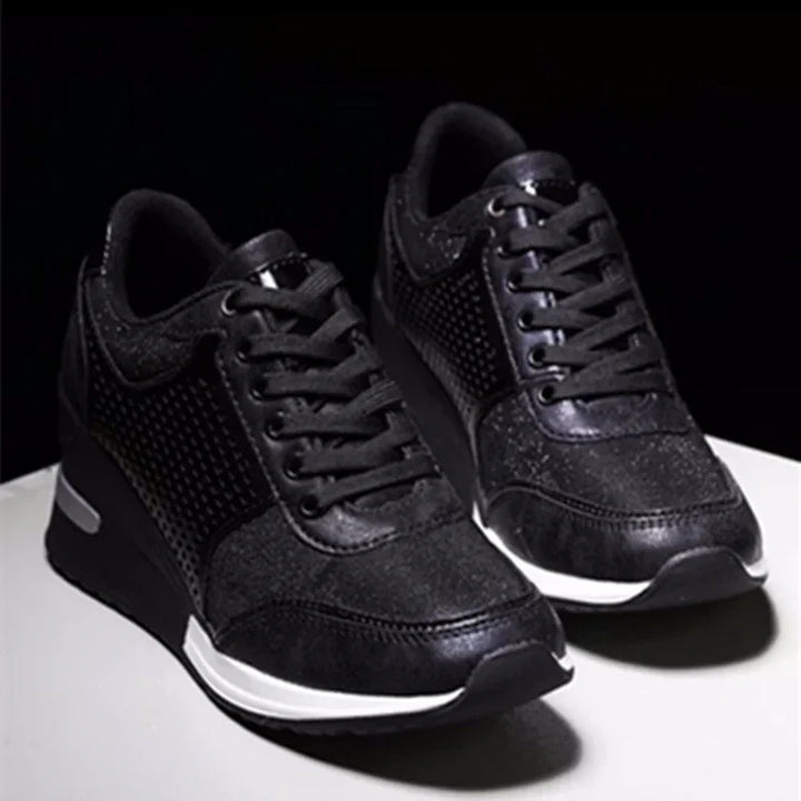 Pair of black athletic sneakers with mesh and leather details on white surface