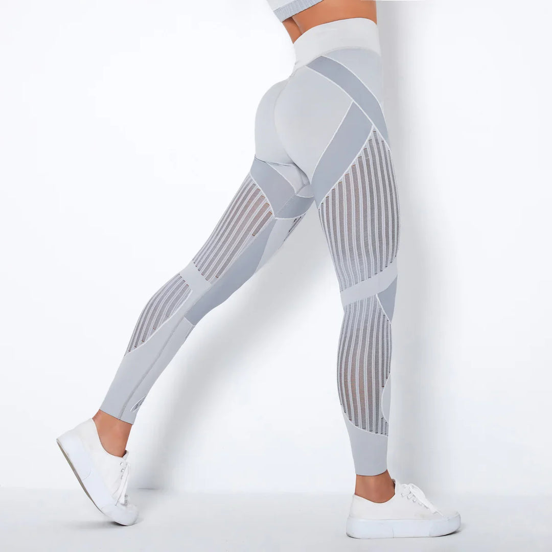 Woman wearing stylish gray and white mesh detail leggings with white sneakers against white background