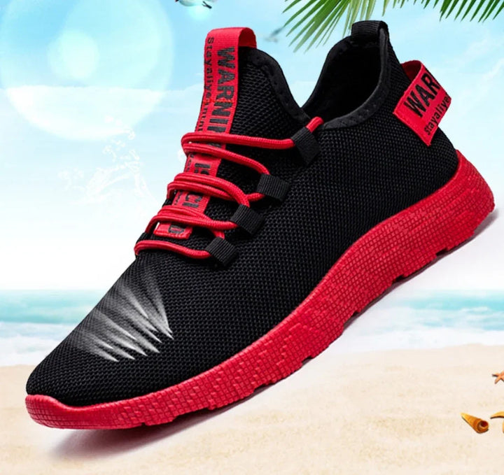 Black and red lightweight breathable athletic sneaker with red sole and laces on beach background