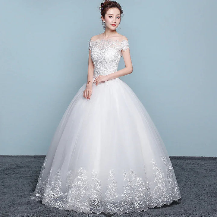 Bride in elegant off-shoulder white lace wedding gown with floral embroidery on skirt