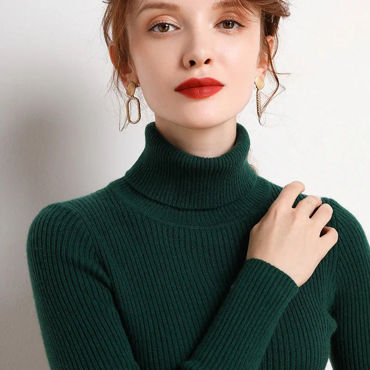 Woman wearing dark green ribbed turtleneck sweater and gold geometric earrings with red lipstick