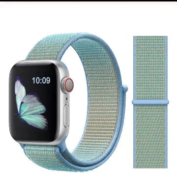 Apple Watch with turquoise woven nylon band and butterfly watch face showing 10:09 time