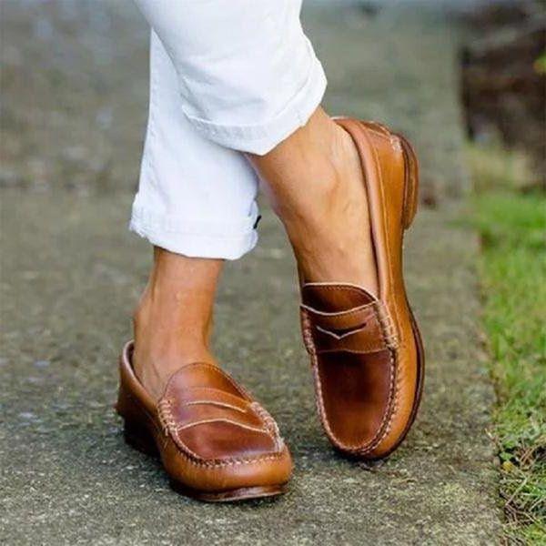 Close-up of tan leather loafers worn with white rolled-up pants on outdoor pavement