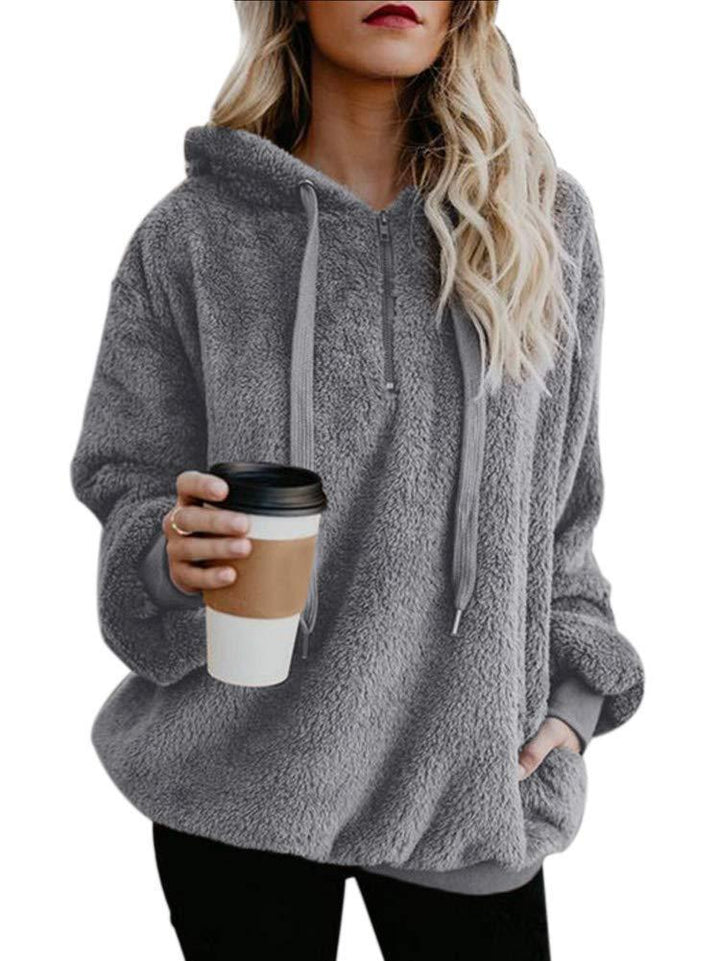 Woman wearing cozy gray fleece hoodie holding takeaway coffee cup with black lid