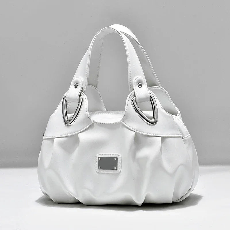 White leather handbag with silver hardware and double handles on gray background