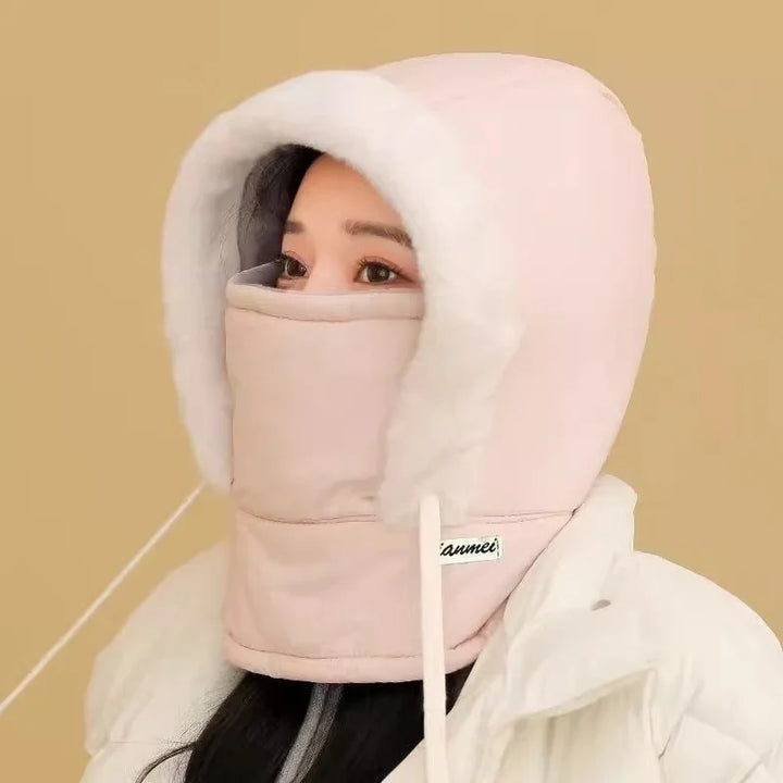 Woman wearing light pink insulated winter hood with white fur trim and matching face cover