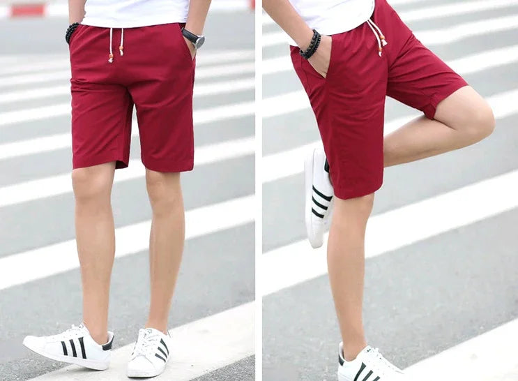 Men's casual red drawstring shorts worn with white sneakers on urban street crosswalk