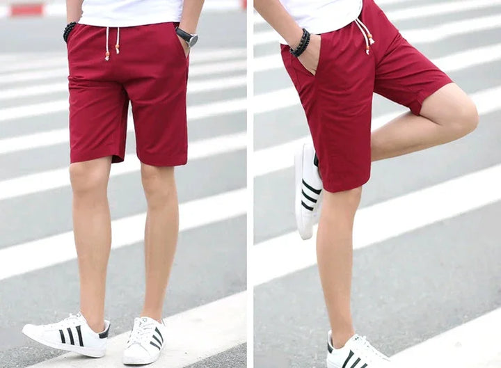 Men's casual red drawstring shorts worn with white sneakers on urban street crosswalk