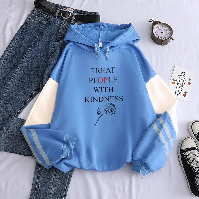 Blue hoodie with white sleeves and text Treat People With Kindness, paired with jeans, black belt, clock, and sneakers