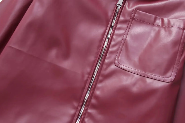 Close-up of burgundy leather jacket with silver zipper and stitched pocket detail
