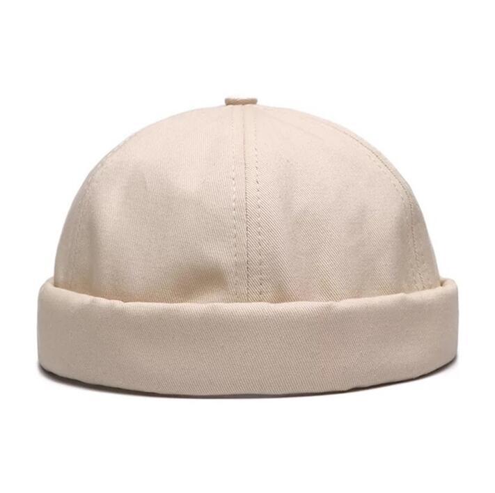 Beige cotton docker cap with rolled brim and top button detail on white background