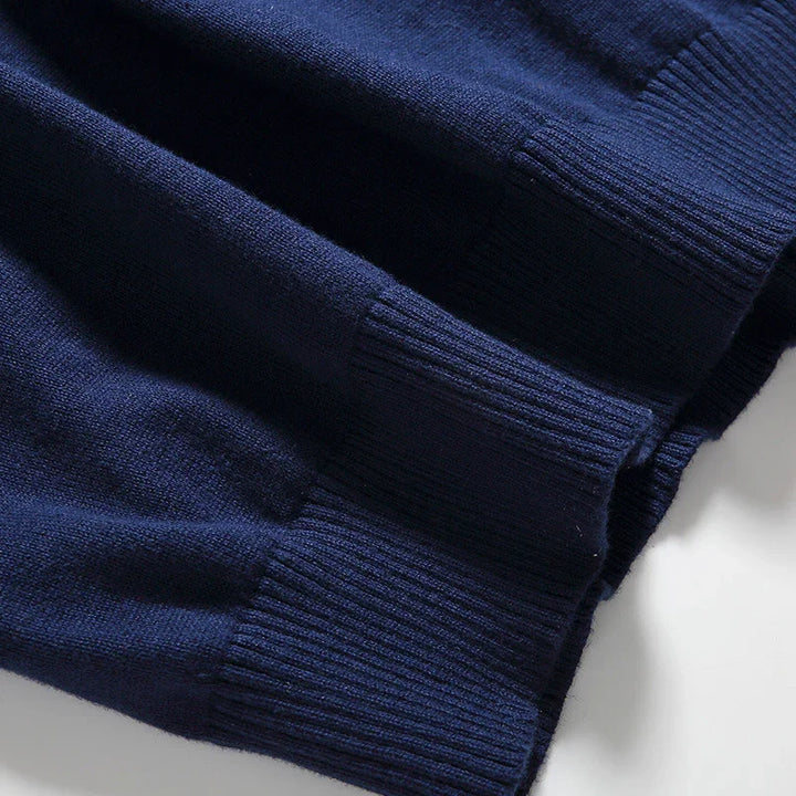 Close-up of navy blue ribbed knit sweater fabric with folded cuffs on white background