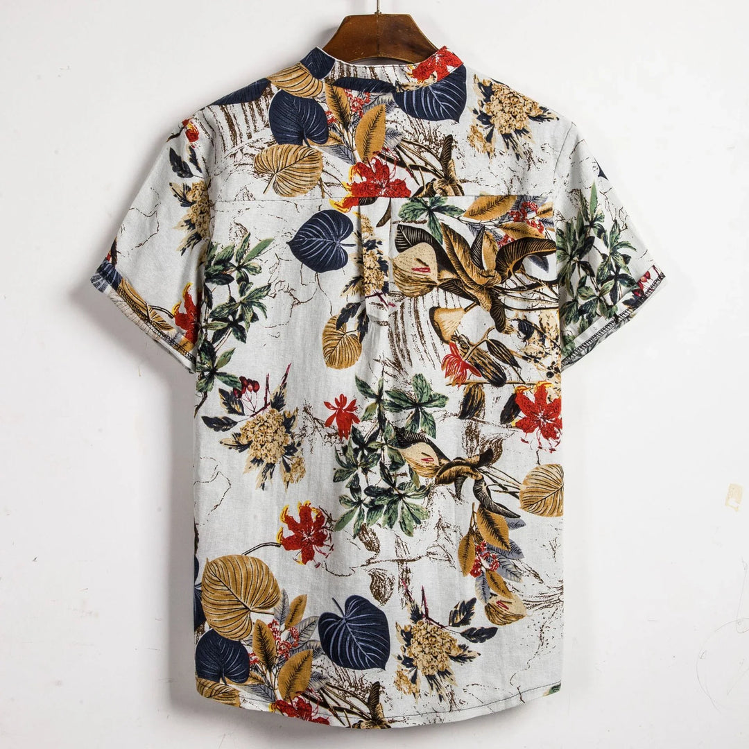 Back view of short sleeve tropical floral print shirt with green, red, yellow, and navy leaves on white background