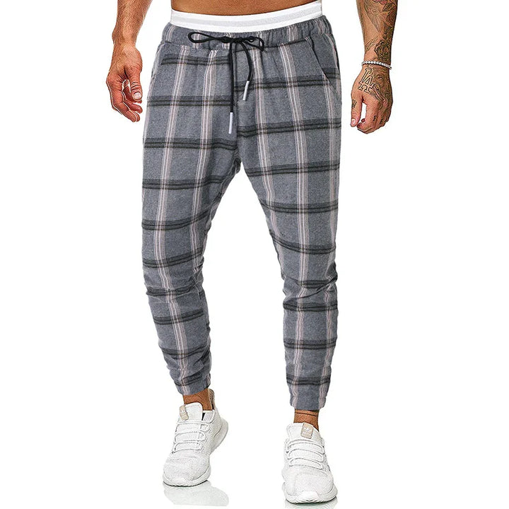Men's gray plaid jogger pants with black drawstring, cuffed ankles, worn with white sneakers