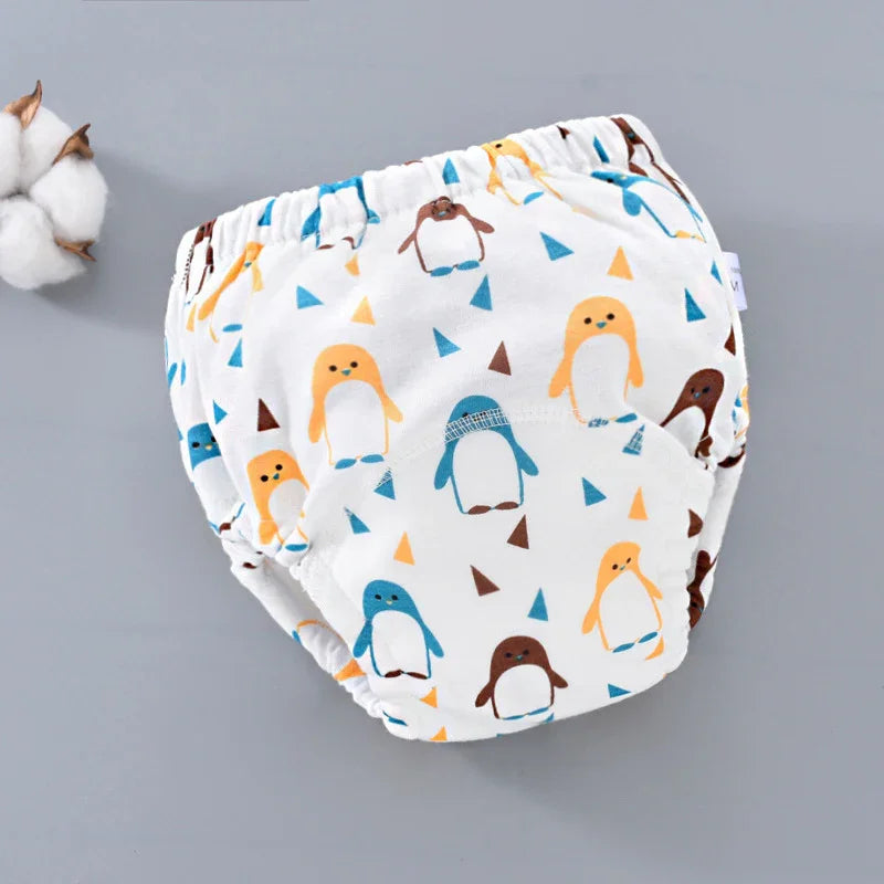 White baby training pants with colorful penguin print on gray background and cotton flower