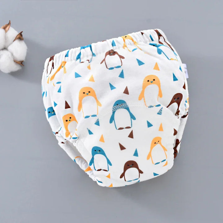 White baby training pants with colorful penguin print on gray background and cotton flower