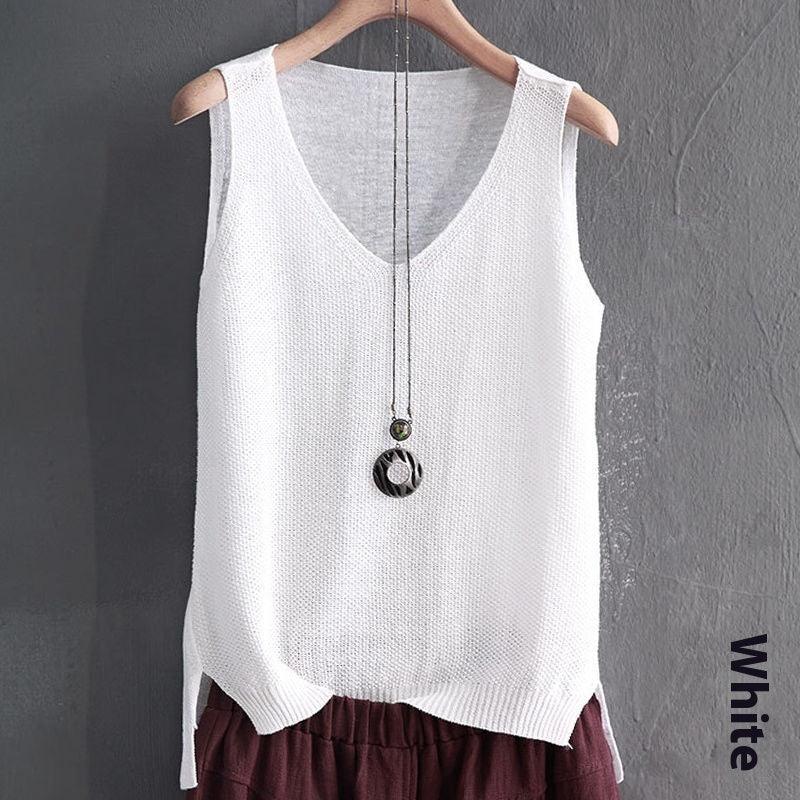 White knitted sleeveless V-neck sweater vest on hanger with pendant necklace against gray wall
