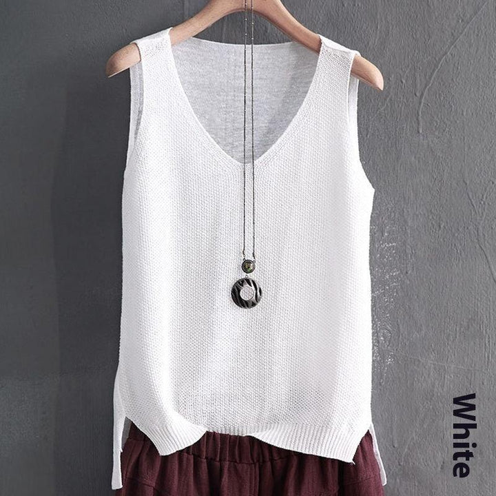White knitted sleeveless V-neck sweater vest on hanger with pendant necklace against gray wall