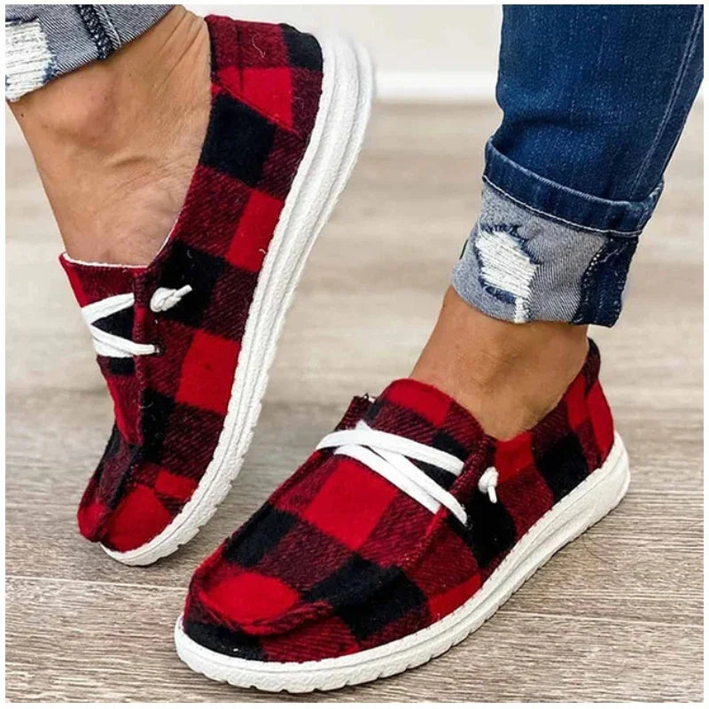 Casual red and black plaid slip-on shoes with white laces, worn with cuffed distressed jeans