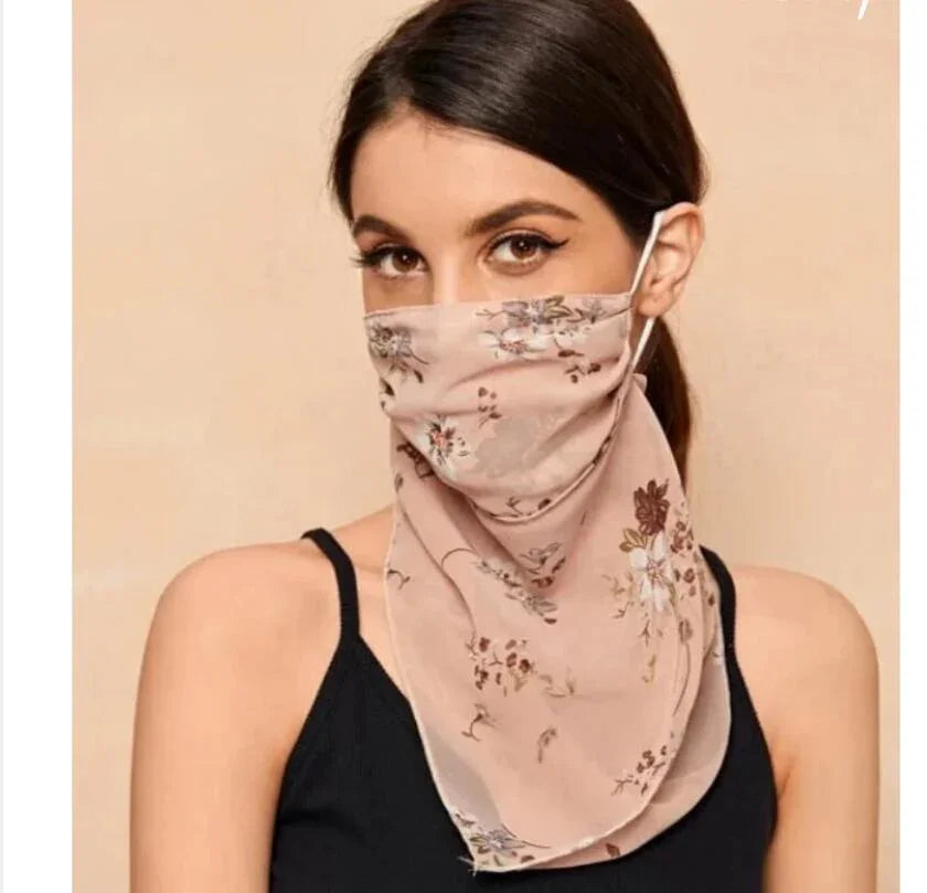Woman wearing a floral print pink face cover scarf with black tank top on beige background