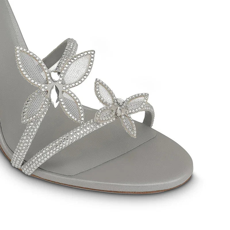 Close-up of a gray sandal with rhinestone butterfly embellishments on straps