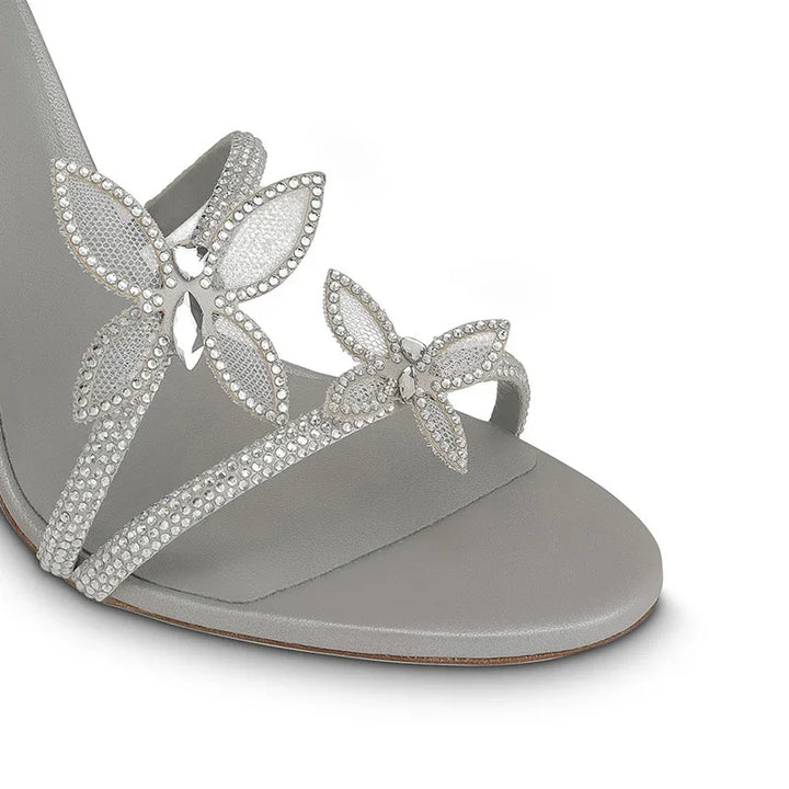 Close-up of a gray sandal with rhinestone butterfly embellishments on straps