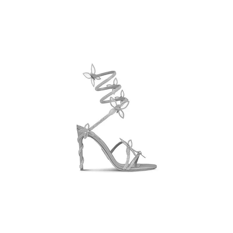 elegant silver high-heeled sandal with butterfly details and ankle wrap on white background