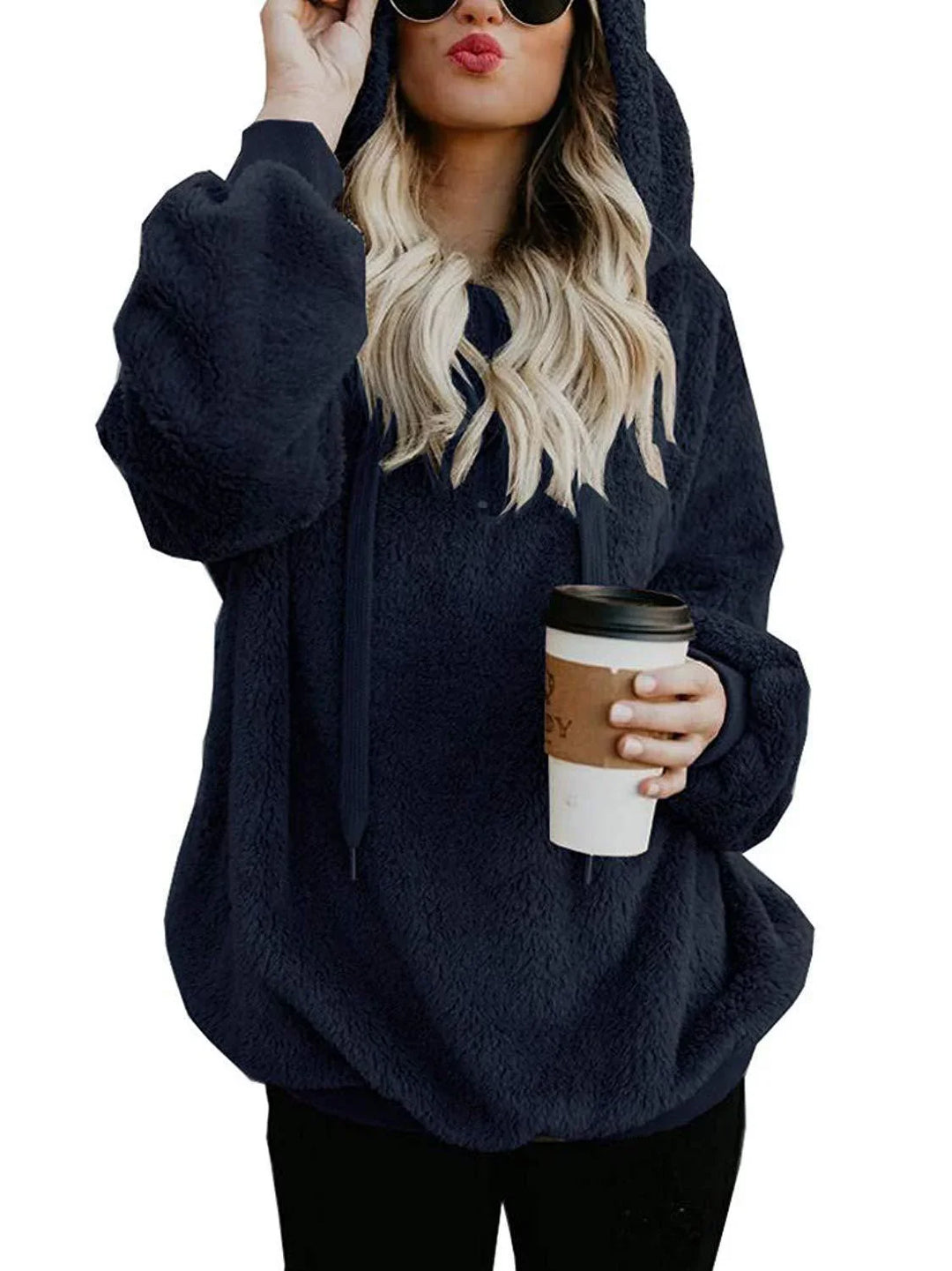 Woman wearing oversized black fleece hoodie holding takeaway coffee cup
