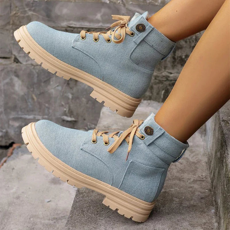 Light blue fabric ankle boots with beige laces and rugged tan soles on concrete steps