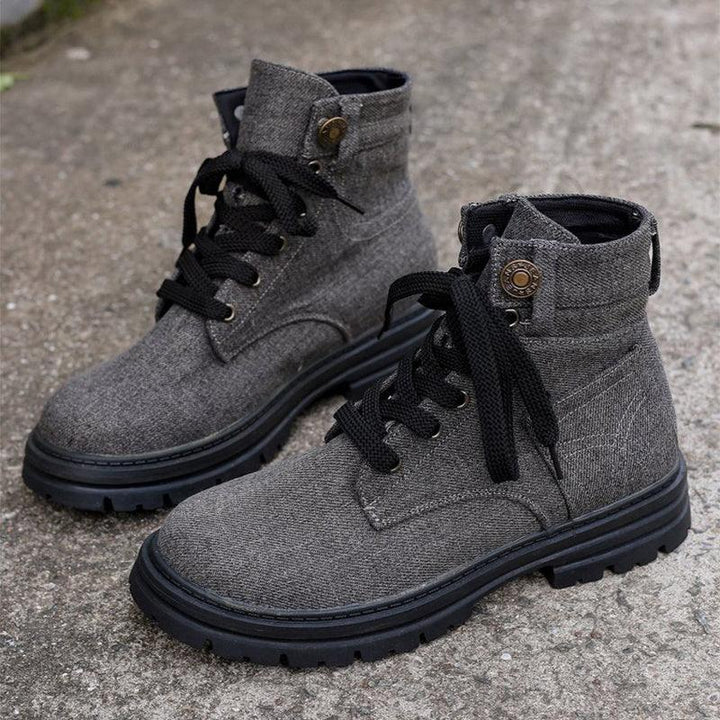Gray fabric high-top boots with black laces and rugged black soles on concrete surface