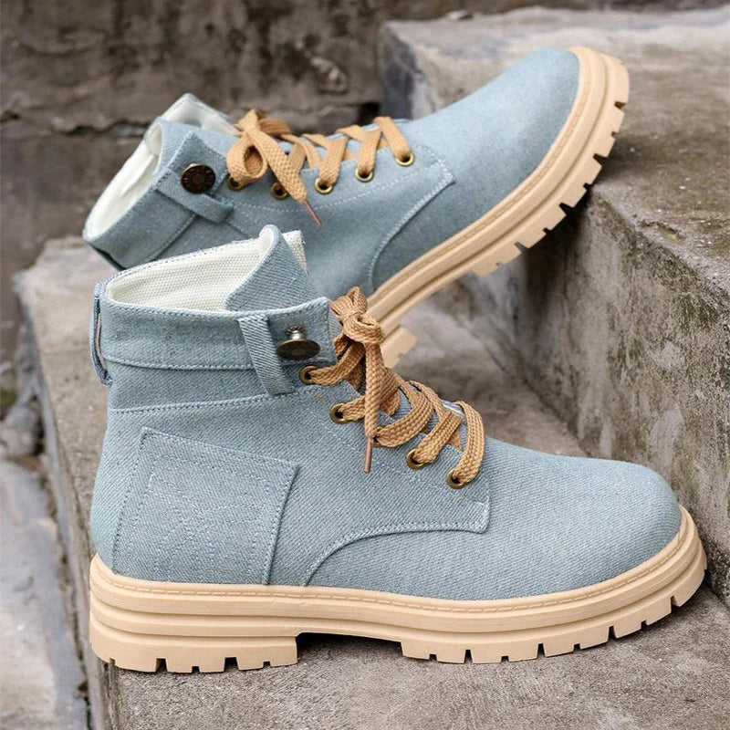 Light blue denim hiking boots with beige laces and rugged beige soles on stone steps