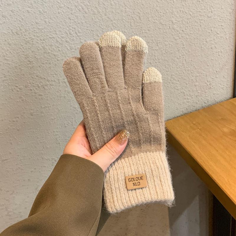 Hand holding beige and cream knitted gloves with touchscreen fingertips and Golove NLD label