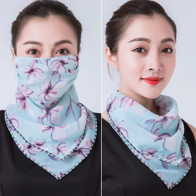 Woman wearing a light blue floral face scarf styled as a mask and a neck scarf, against a plain background