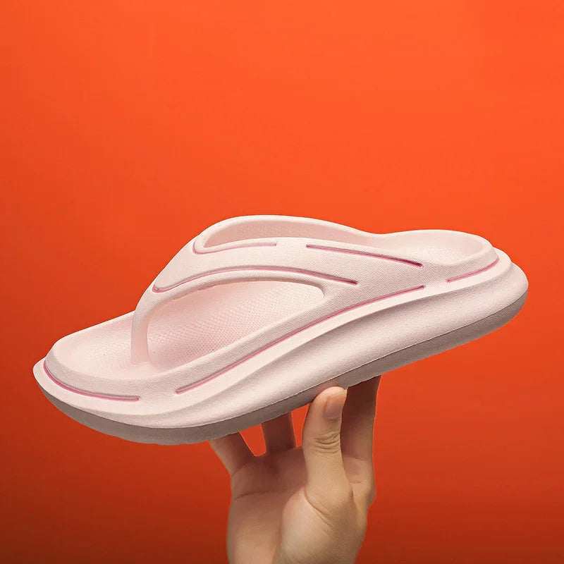 Hand holding light pink cushioned flip-flop sandal with textured sole on orange background