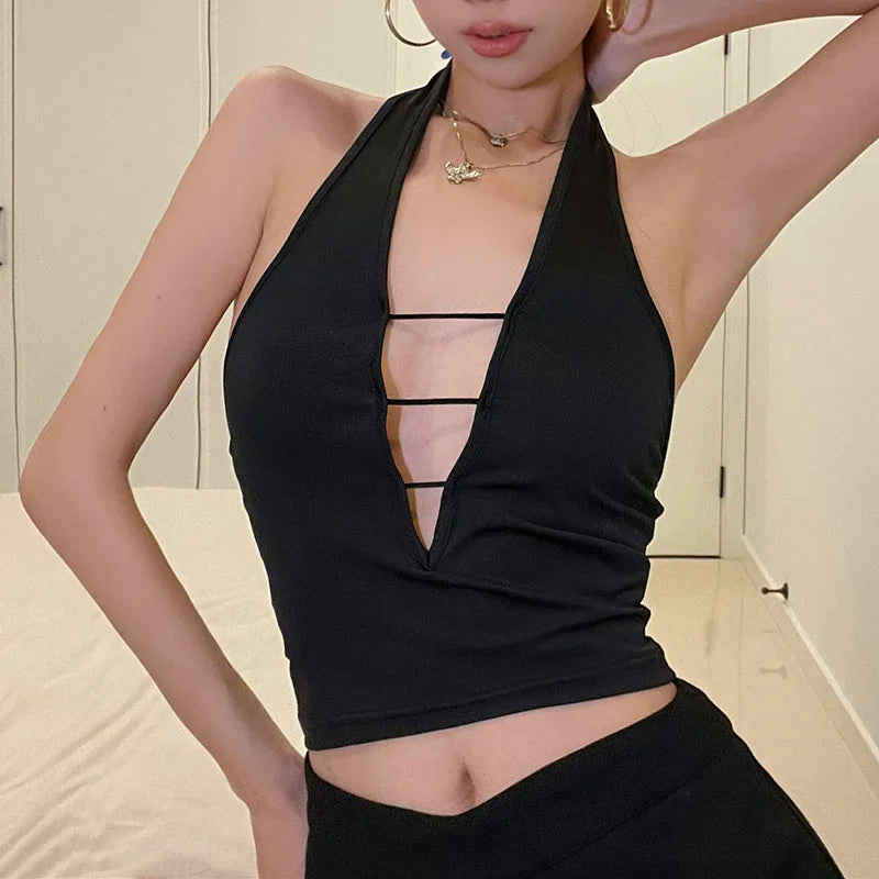 Woman wearing a black halter top with deep V neckline and horizontal strap details indoors