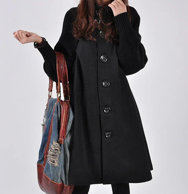 Woman wearing black buttoned coat holding large distressed denim and leather handbag