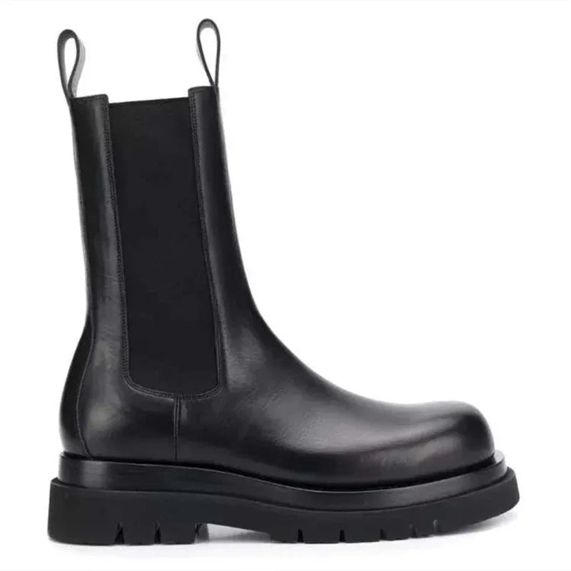 Black leather Chelsea boot with thick rubber sole and pull tabs on white background